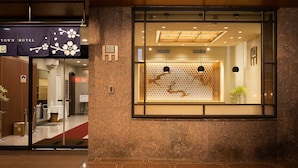 A hotel entrance with a reception desk, a glass door, and a sign indicating a 24-hour service area. - Shizuoka Town Hotel (Shizuoka)