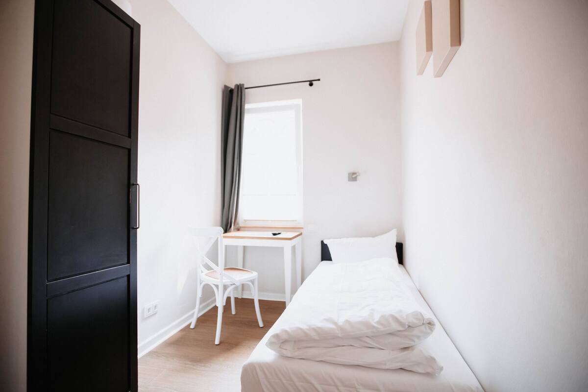 Un dormitorio con una cama, un escritorio y una silla.