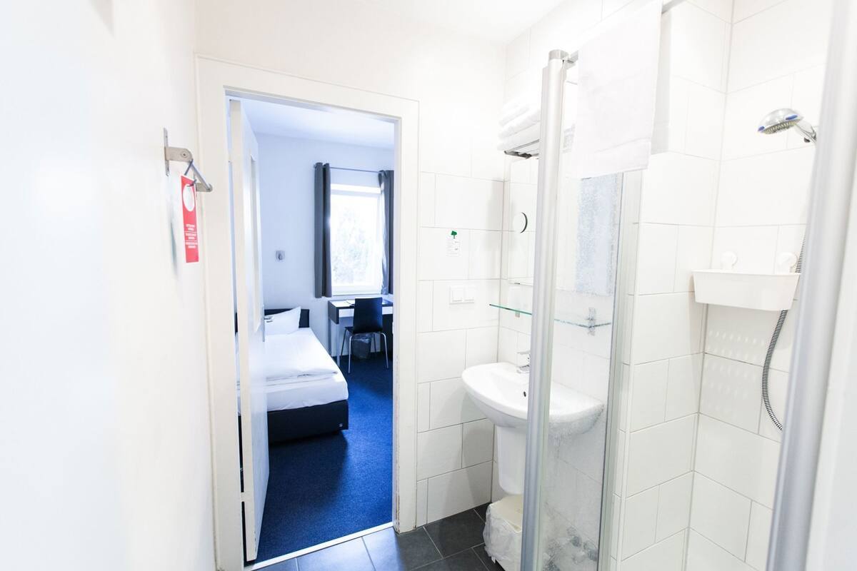 Un baño de hotel con ducha, inodoro y lavabo.
