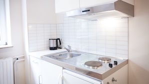 A modern kitchen with white cabinetry, a stainless steel sink, and a built-in stove. - Arcade Hotel Hamburg (Hamburg)