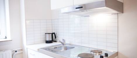 A modern kitchen with white cabinetry, a stainless steel sink, and a built-in stove.
