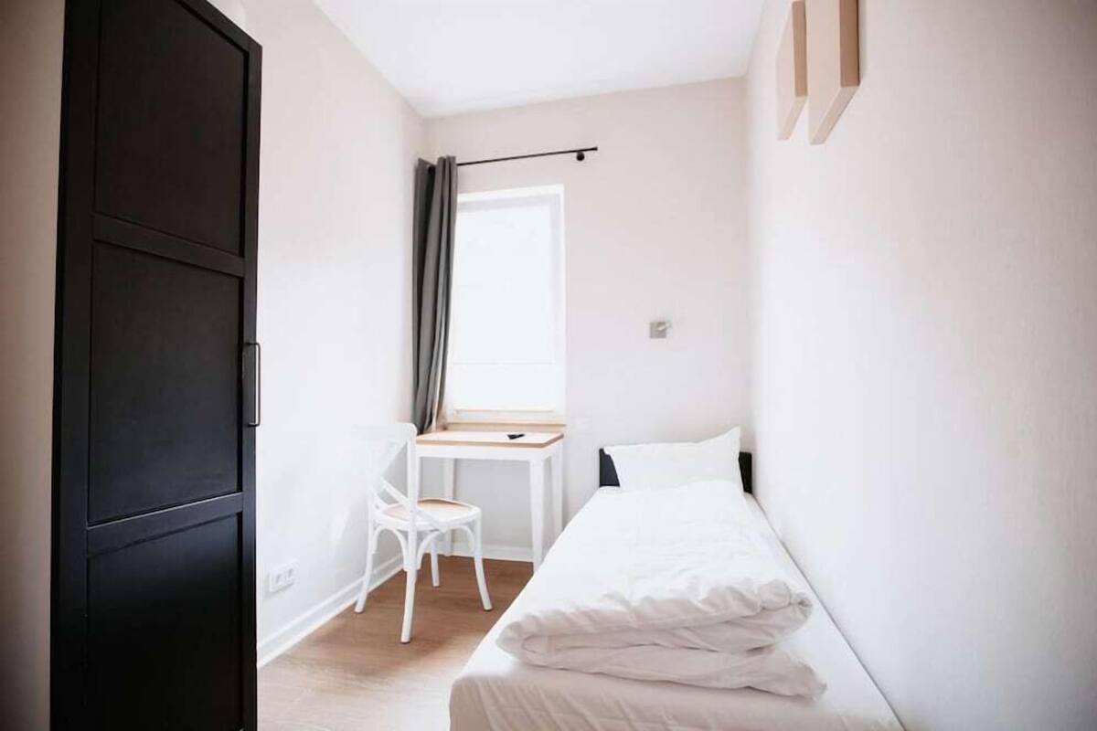 Un dormitorio con cama, escritorio, silla y armario.