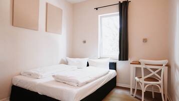 A bedroom with a bed, a desk, and a chair.