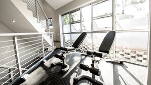 A gym with a bench press, a staircase, and large windows. - Insignia Lifestyle (Sandton)