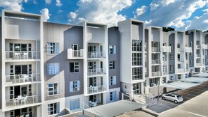 A modern multi-story residential building with balconies, a parking area, and a clear sky. - Insignia Lifestyle (Sandton)