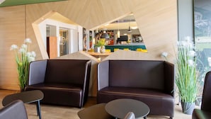 A modern reception area with leather sofas, a reception desk, and a view of the interior. - B&B Hotel Augsburg-Süd (Augsburg)