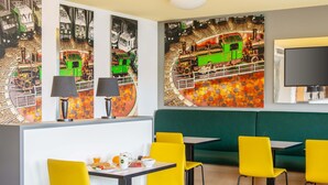 A restaurant with yellow chairs, a green booth, and a wall with a train mural. - B&B Hotel Augsburg-Süd (Augsburg)