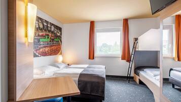 A hotel room with two beds, a desk, a chair, a TV, and a window with curtains.