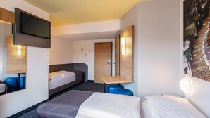 A hotel room with a bed, a desk, a chair, a TV, and a door. - B&B Hotel Augsburg-Süd (Augsburg)