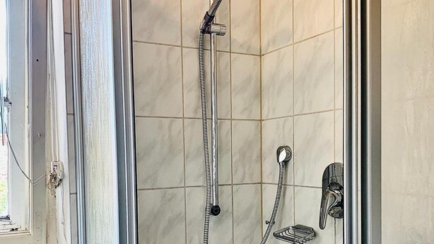 A shower with a handheld showerhead and a wall-mounted faucet. - Gästehaus Hohe Tannen (Garmisch-Partenkirchen)