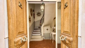 Eine Holztür mit verzierten Griffen, eine Treppe mit Geländer und ein kleiner Tisch mit einem dekorativen Gegenstand.