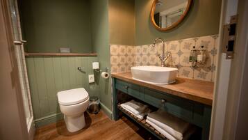 A bathroom with a white toilet, a wooden vanity with a sink, and a mirror.