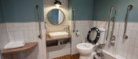 A bathroom with a white toilet, a sink, a mirror, and a shower area.