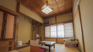 Et traditionelt japansk rum med tatamimåtter, et lavt bord, en polstret stol og en skydedør.
