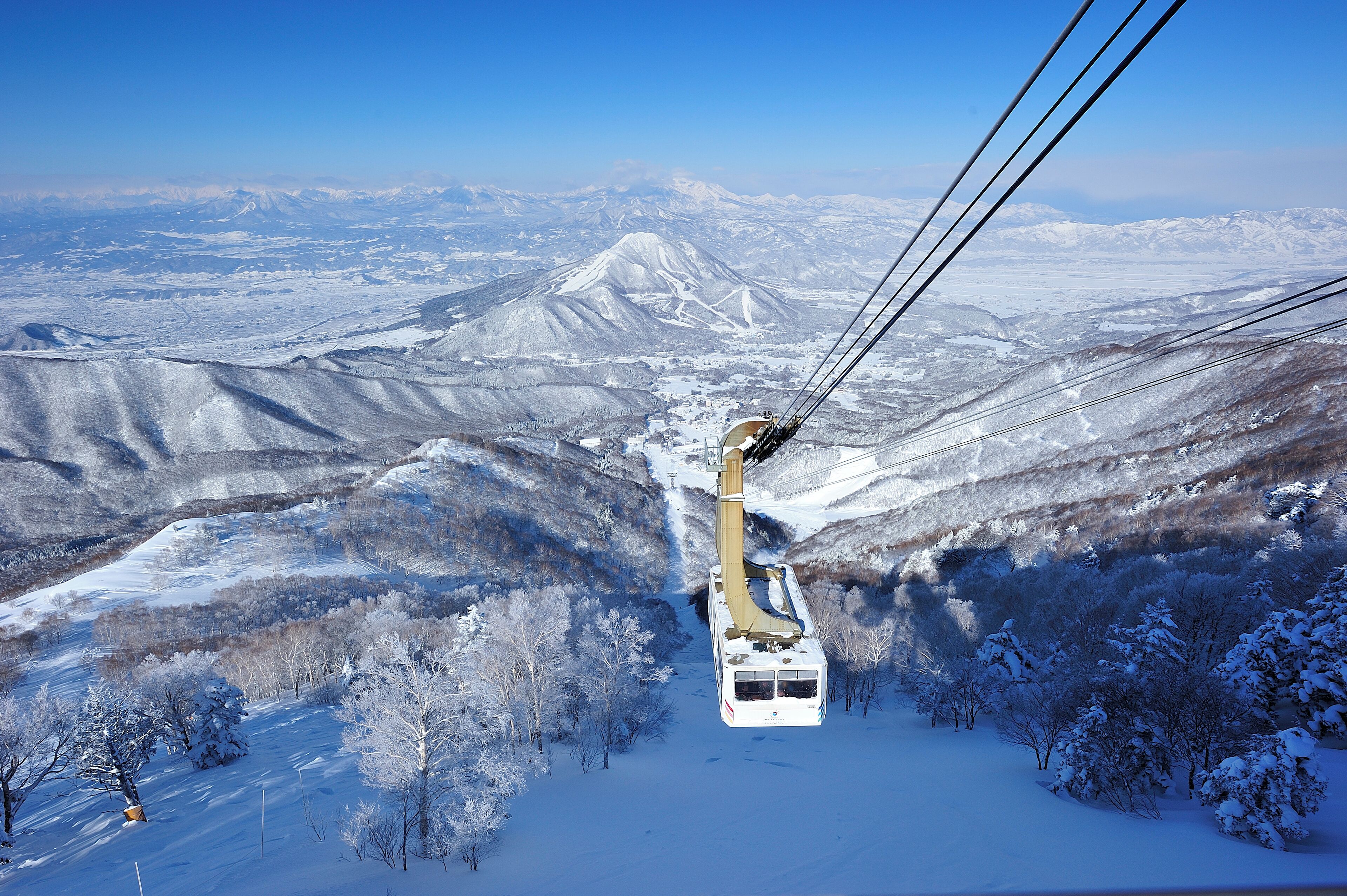 Um teleférico atravessa uma paisagem montanhosa coberta de neve.