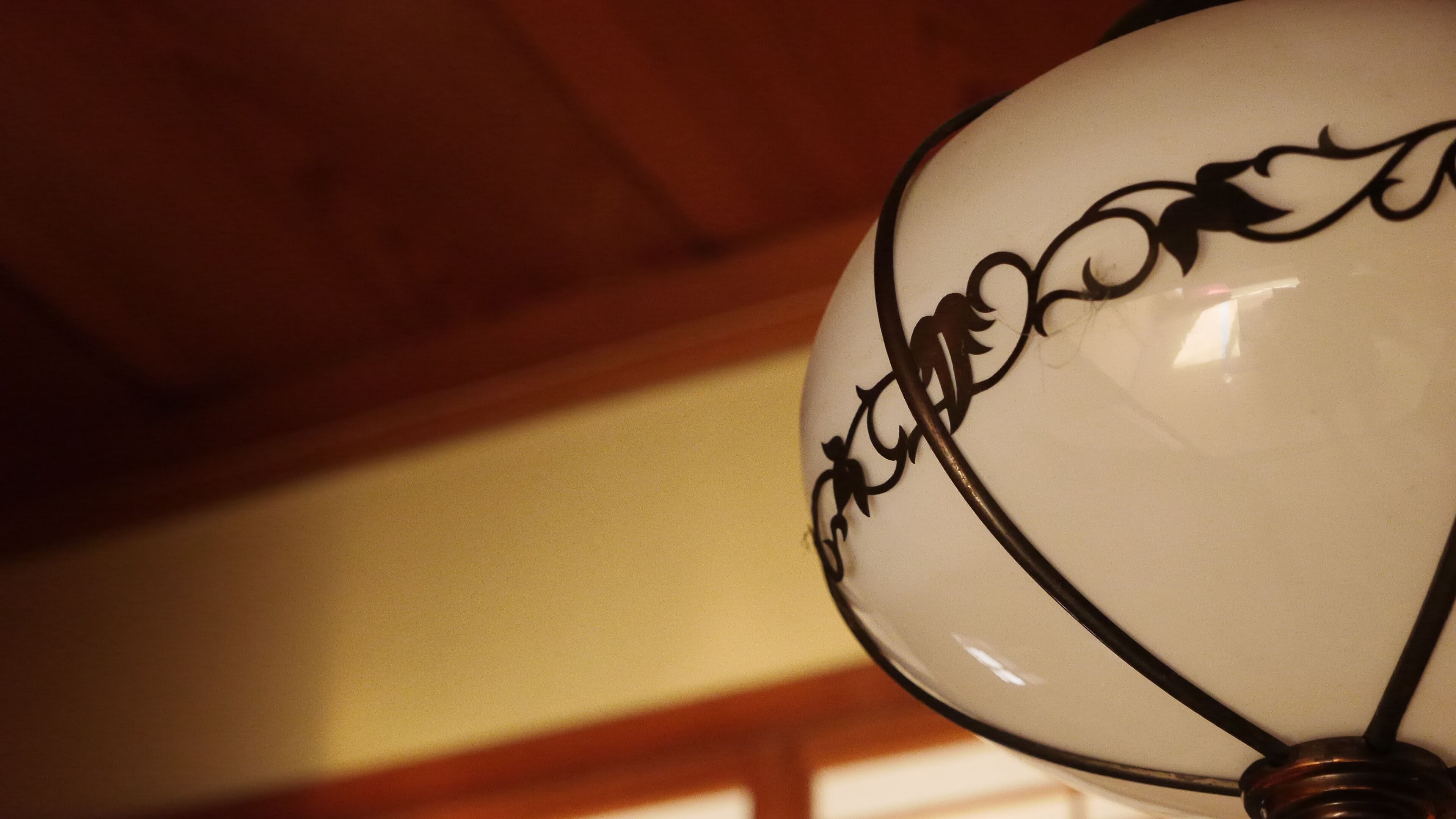 A close-up of a white ceiling light fixture with a decorative black design.
