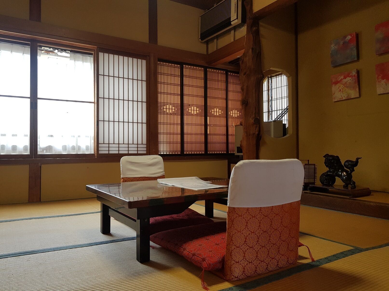 Een traditionele Japanse kamer met tatami vloerbedekking, een lage tafel, een zachte stoel en verschuifbare shoji deuren.