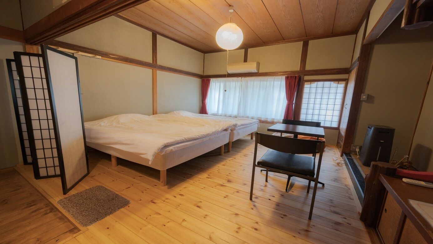 Una habitación con cama, escritorio, silla y ventana con cortinas.