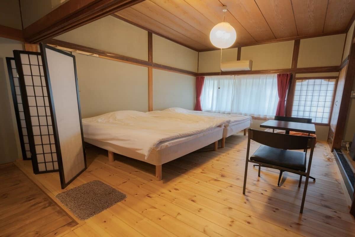 Huone, jossa on sänky, työpöytä, tuoli ja ikkuna, jossa on verhot.