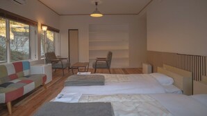 Et moderne hotelværelse med to senge, en sofa, et lille bord og en stol.