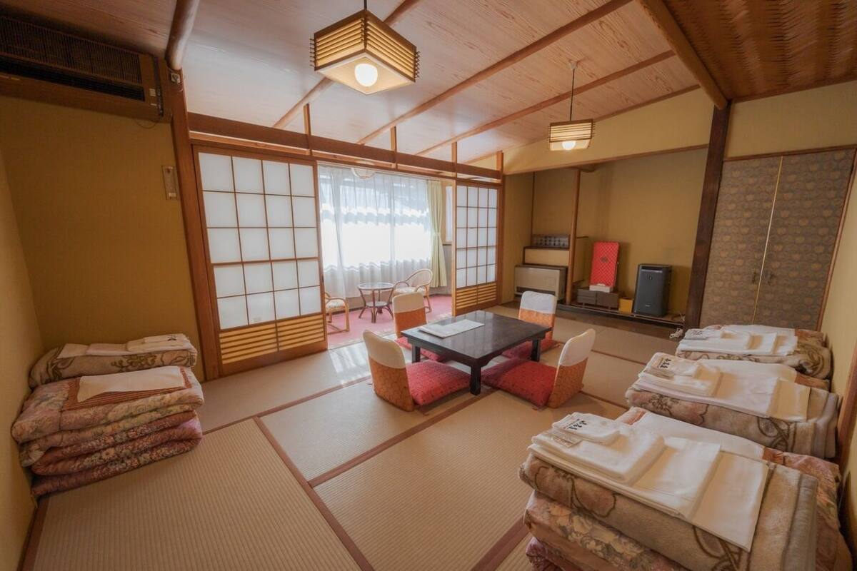 Perinteinen japanilainen huone, jossa on tatamimatto, matala pöytä tyynyineen ja liukuovi.