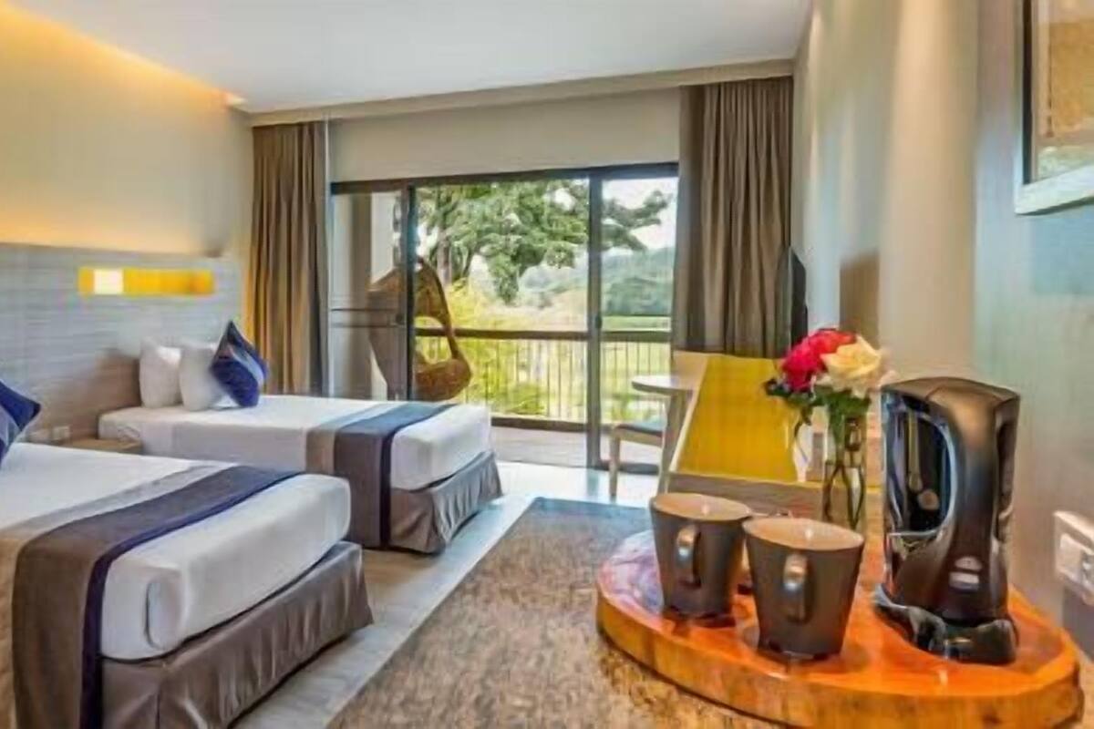 Une chambre d’hôtel avec deux lits, une table à manger avec des chaises, une télévision et un balcon avec vue.