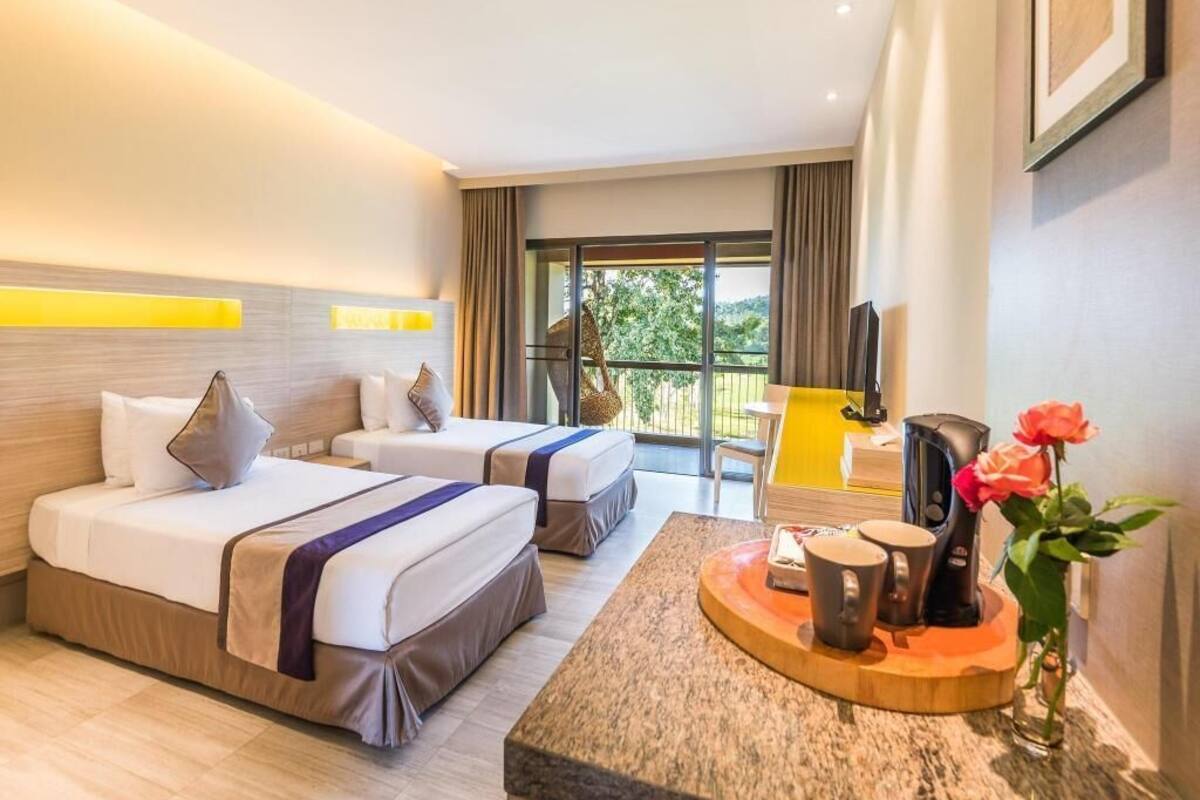 Une chambre d’hôtel avec deux lits, une table basse avec un plateau, une machine à café et une vue sur l’extérieur.