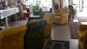 Un vaste espace de vie comprenant plusieurs canapés et fauteuils, une table basse et un grand miroir.