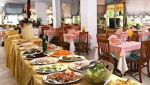 Un comedor con varias mesas, cada una cubierta por un mantel, y una variedad de platos exhibidos en las mesas.