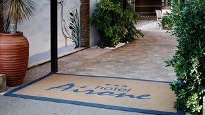 The exterior of the Airone Hotel with a prominent sign, a covered entrance, and a doormat with the hotel's name. - Airone (Rimini)