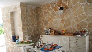 A stone-walled room with a breakfast setup including a table, chairs, and a buffet counter. - B&B Puglia Vista Mare (Monopoli)