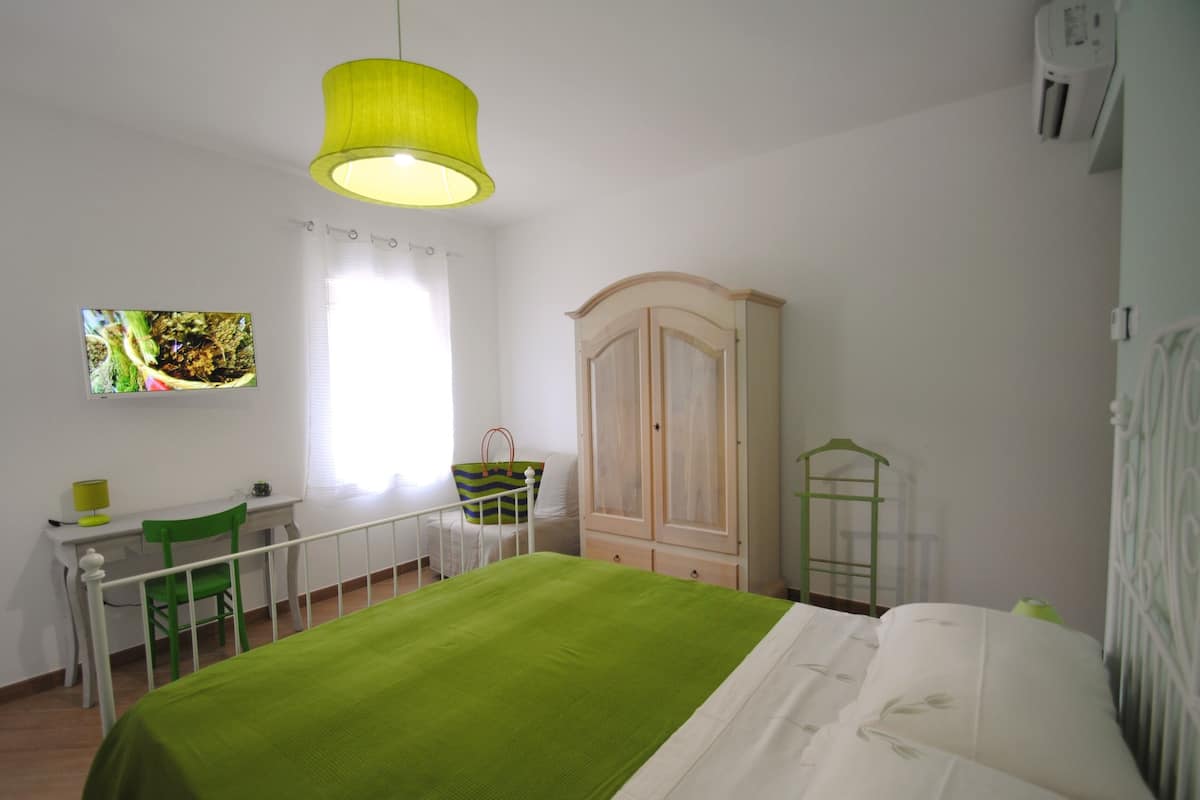Un dormitorio con cama, escritorio, silla, armario e iluminación colgante.
