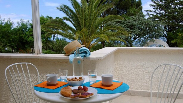 A small outdoor table with a white metal chair, a bowl of cookies, a plate of pastries, and a bottle of water. - B&B Puglia Vista Mare (Monopoli)