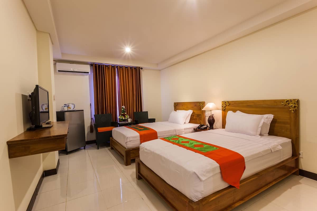 A hotel room with two beds, a desk, a TV, and a small kitchenette.