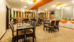 A conference room with multiple tables and chairs, a large screen, and a buffet setup. - Mahatma Residence (Denpasar)