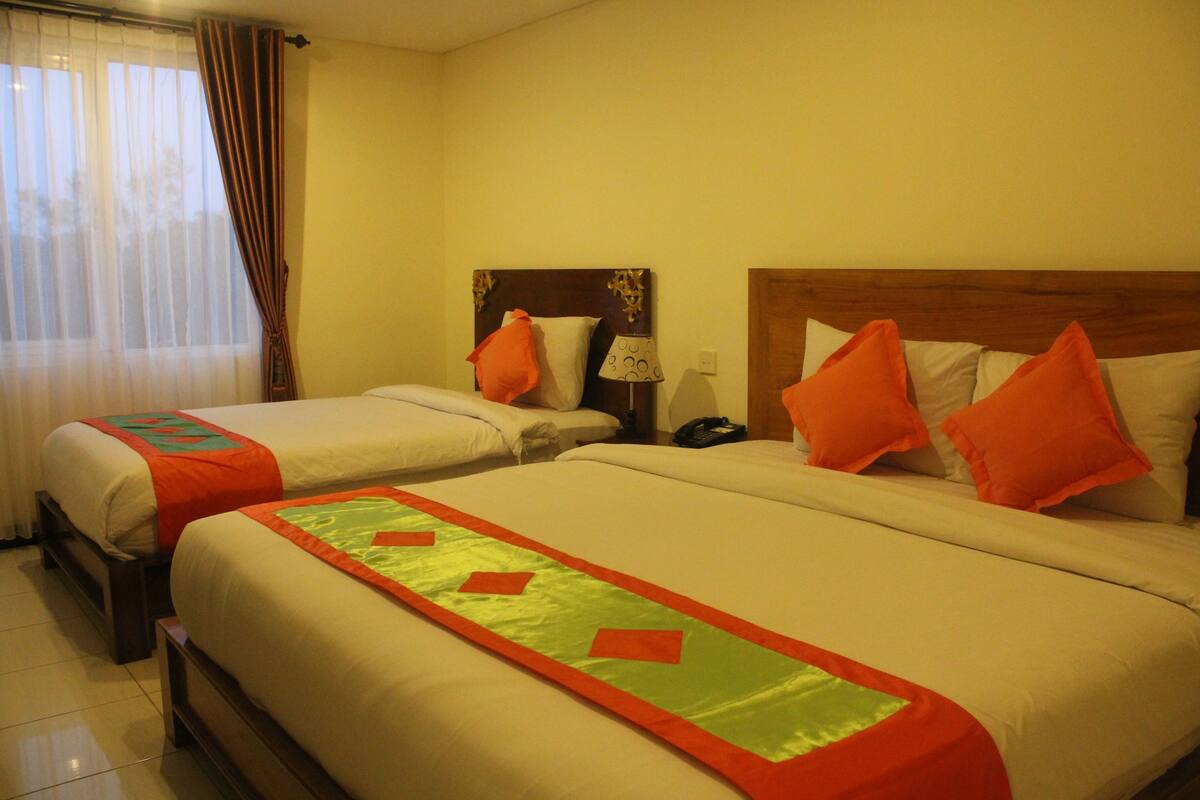 A hotel room with two beds, each with a headboard, a nightstand, and a lamp.