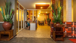 A reception area with a receptionist, a desk, and a seating area with a table and chairs. - Mahatma Residence (Denpasar)