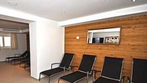 A waiting area with black chairs and a wooden wall with a mirror. - Appart Residence Kristall by Skinetworks (Saalbach-Hinterglemm)