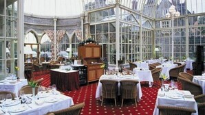 A conservatory with tables set for dining, large windows, and a red carpet.