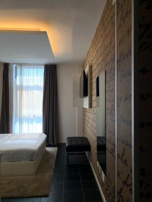 A hotel room with a bed, a bench, a television, and a wall with handwritten notes. - La Rocca (Nogarole Rocca)
