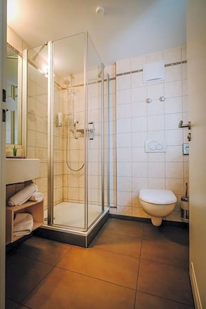 A modern bathroom with a glass-enclosed shower, a toilet, and a vanity with a mirror.