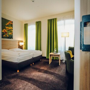 A hotel room with a bed, a desk, a chair, and a lamp. - Europa Bamberg (Bamberg)
