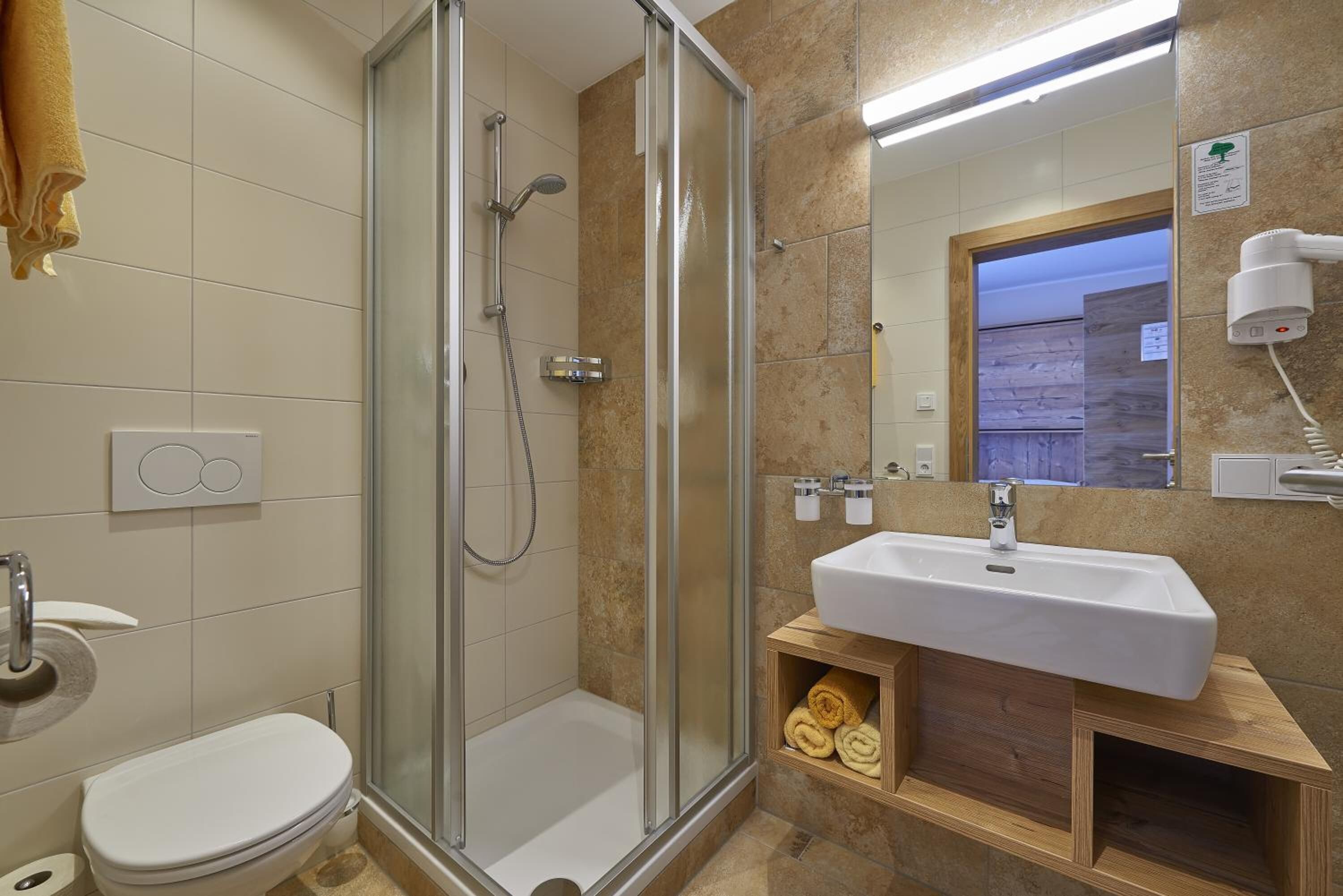 Une salle de bain moderne avec une douche à parois de verre, un lavabo blanc et un meuble-lavabo en bois.