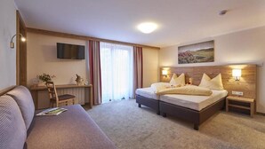 A hotel room with a bed, a desk, a TV, and a painting on the wall. - Pension Gabi (Saalbach-Hinterglemm)
