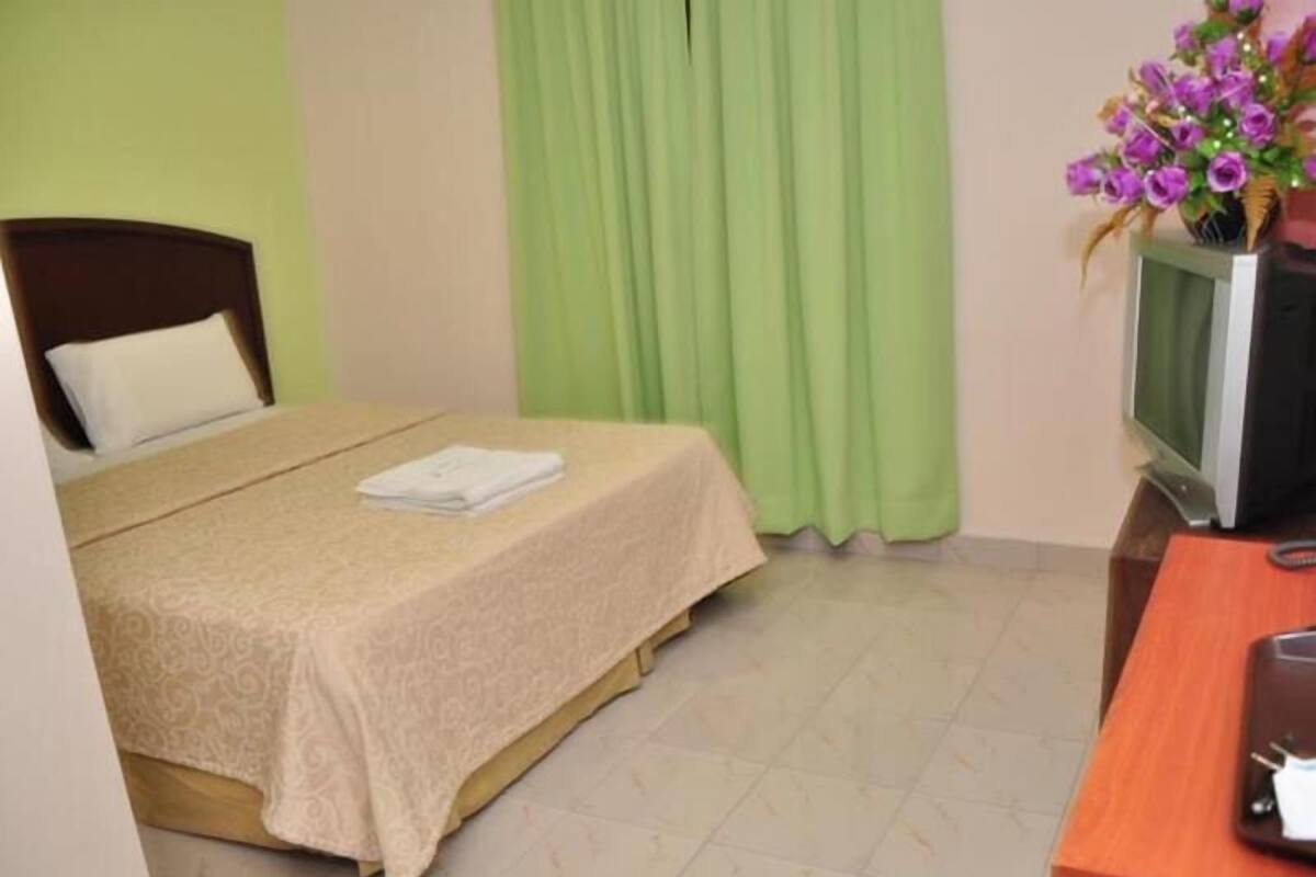 A hotel room with a bed, a television, and a desk with a computer.