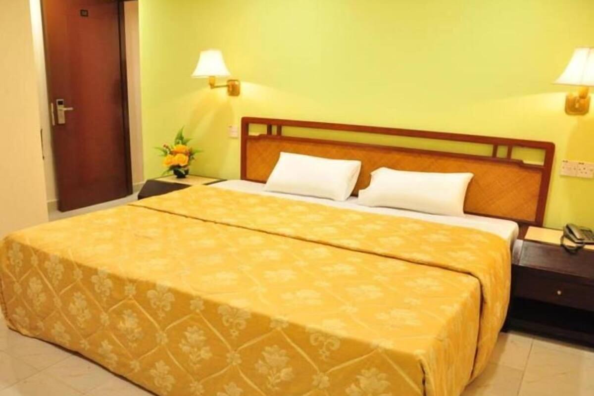 A hotel room with a bed, two bedside lamps, a nightstand, and a door.