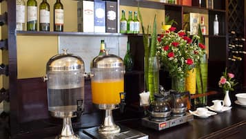 A bar area with two beverage dispensers, a coffee machine, and a selection of wine bottles on shelves.