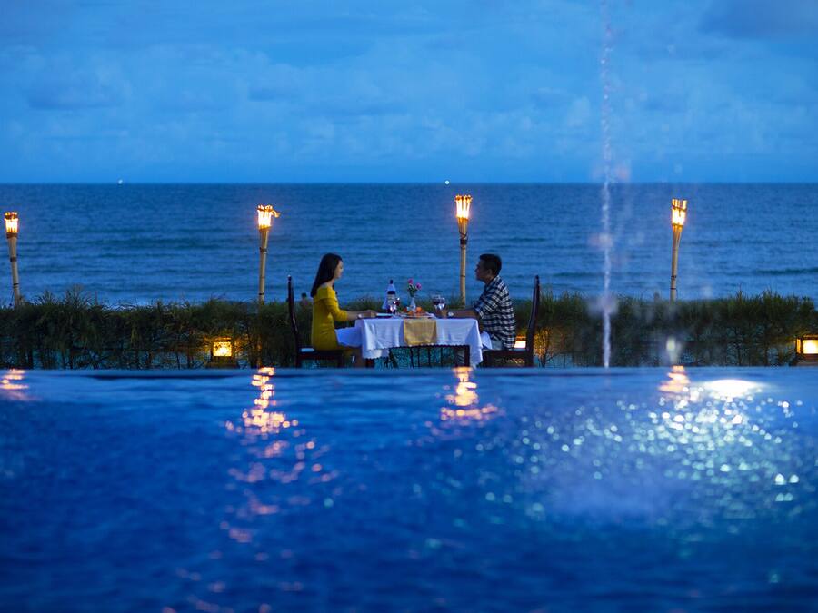 A dining table with a view of the ocean, surrounded by decorative torches.