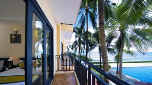 Une chambre d’hôtel avec un balcon donnant sur une piscine et l’océan.