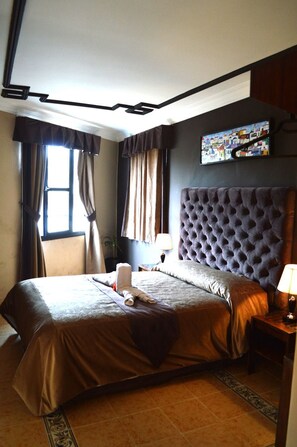 A hotel room with a large bed, a headboard, a nightstand, a lamp, and a painting on the wall. - Beau Rivage (Essaouira)